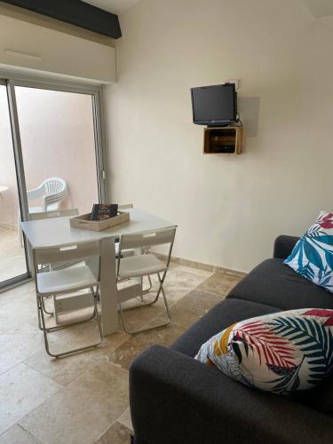 ein Wohnzimmer mit einem Sofa, einem Tisch und einem TV in der Unterkunft Le Calochan in Le Grau-dʼAgde