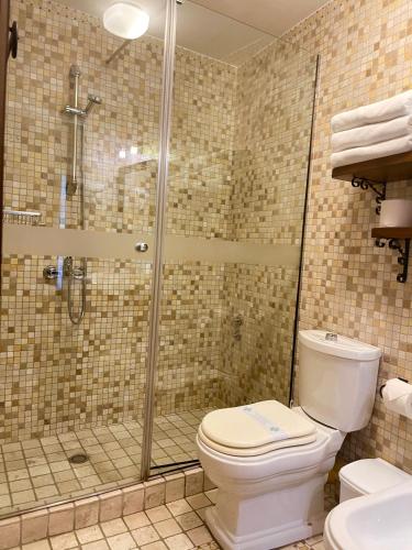 a bathroom with a toilet and a glass shower at Hotel Mangalemi in Berat