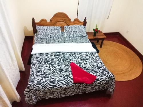 a bed with black and white sheets and two red pillows at Shimbwe Meadows Home in Moshi