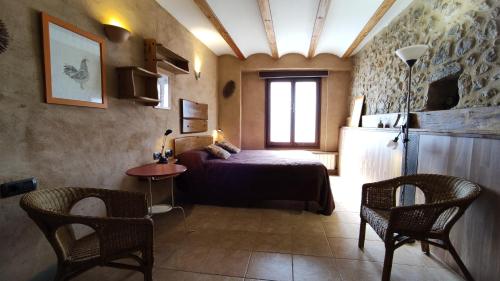 a bedroom with a bed and a table and chairs at Mas Ca La Coixa in Tortellá