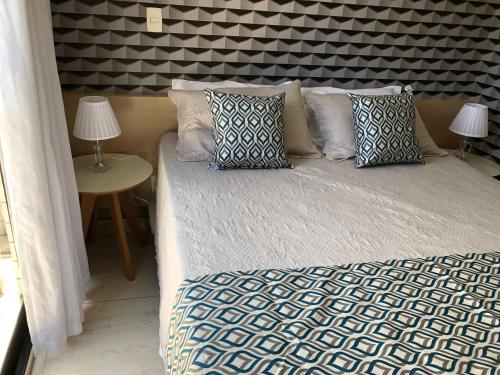 uma cama com almofadas num quarto em Flat à beira mar em João Pessoa