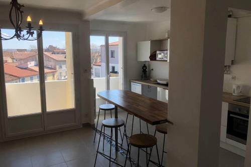 - une cuisine avec une table et des tabourets en bois dans l'établissement Grands Buffets hébergement Appartement Narbonne, à Narbonne