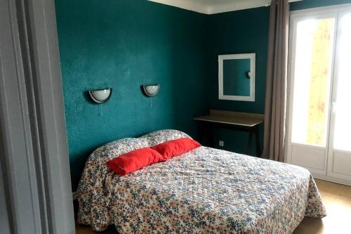 - une chambre verte avec un lit et un oreiller rouge dans l'établissement Grands Buffets hébergement Appartement Narbonne, à Narbonne