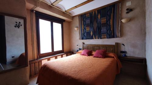a bedroom with a bed with two pink pillows at Mas Ca La Coixa in Tortellá