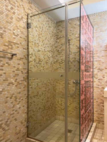 a glass shower in a bathroom with a brick wall at Hotel Mangalemi in Berat