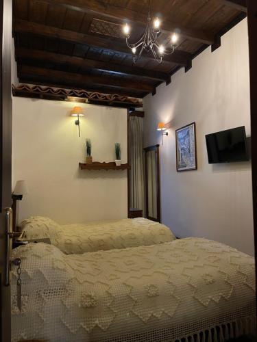 a bedroom with two beds and a tv on the wall at Hotel Mangalemi in Berat