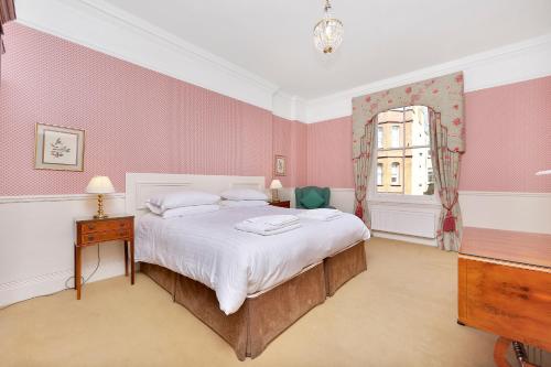 a bedroom with a bed with pink walls and a window at No1 The Mansions By Mansley in London