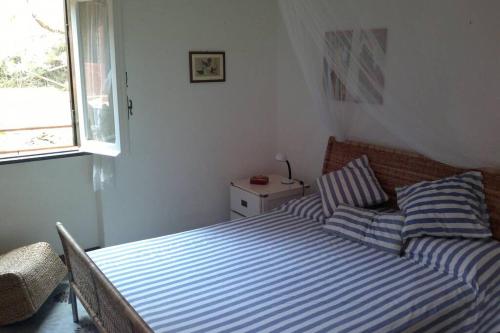 a bedroom with a bed with striped sheets and a window at Casa del pescatore Giannutri in Giannutri