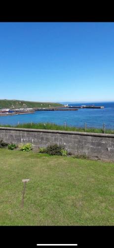 a field with a view of a body of water at Four waves in Thurso
