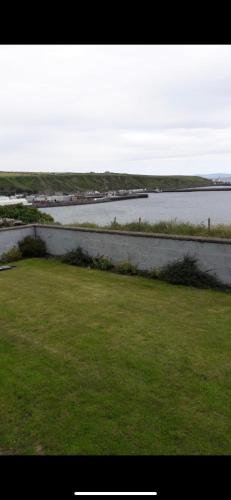 a view of a body of water with a grass field at Four waves in Thurso