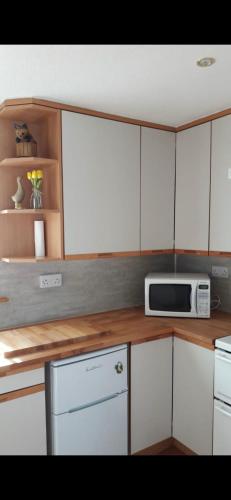 a kitchen with white cabinets and a microwave at Four waves in Thurso