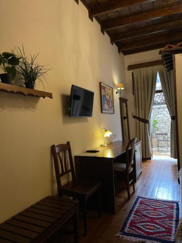 a living room with a desk and chairs and a television at Hotel Mangalemi in Berat