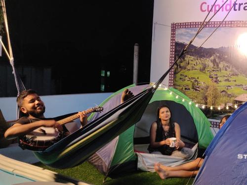 a man and a woman sitting in a hammock in a tent at Cupidtrails Backpacker's Penthouse in Guwahati