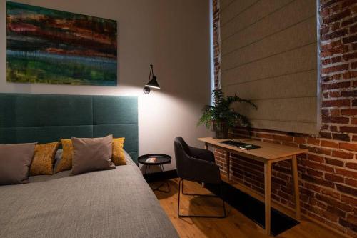 - une chambre avec un lit, une table et un mur en briques dans l'établissement Elegant Apartment Luminis in Krakow's Old City, à Cracovie
