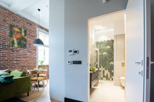 - un salon avec un mur en briques et un canapé vert dans l'établissement Elegant Apartment Luminis in Krakow's Old City, à Cracovie