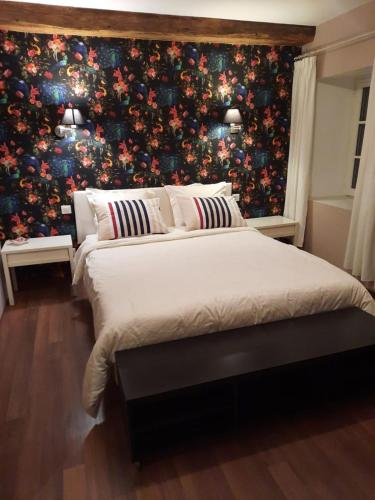 La Grange aux dames في Geville: غرفة نوم بسرير كبير وورق جدران