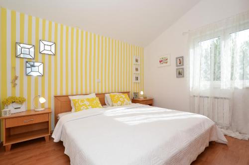a bedroom with a large bed with yellow and white stripes at VIlla Three Palms in Murter