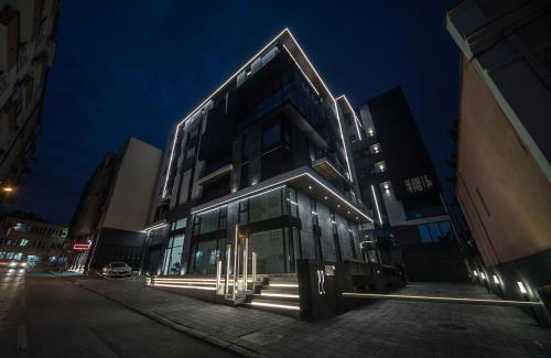 a tall building with lights on a street at night at LUST PREMIUM Apartments in Kragujevac