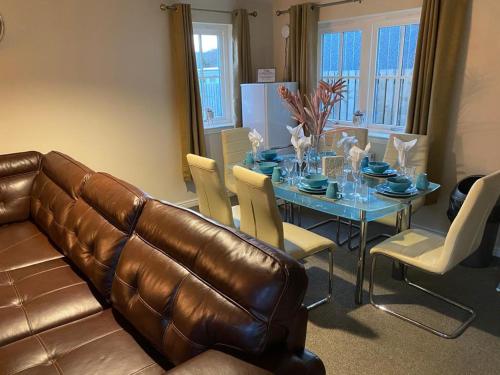 a living room with a table and a leather couch at Balmaha Lodges and Apartments in Balmaha