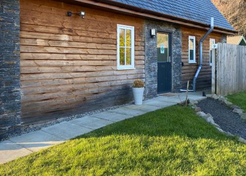 a house with a wooden wall and a door at Balmaha Lodges and Apartments in Balmaha