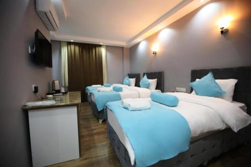 a hotel room with four beds with blue pillows at Grand Atakum Boutıque Hotel in Mahmutlu