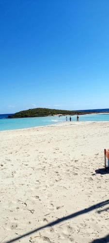 a bench on a beach with people in the water at Panthoma Casa in Ayia Napa