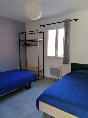 - une chambre avec 2 lits avec des draps bleus et une fenêtre dans l'établissement Les Villas Dorées - Villa Métal face au Mont Ventoux, à Plaisians