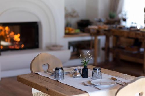 une table en bois avec des assiettes et des ustensiles de cuisine ainsi qu'une cheminée dans l'établissement B&B Il Tabià, à Pieve di Cadore