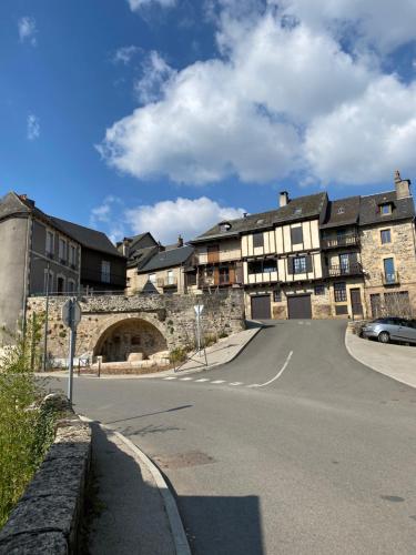 an old stone building with a road in front at Au Pont d’Olt in Saint-Côme-dʼOlt