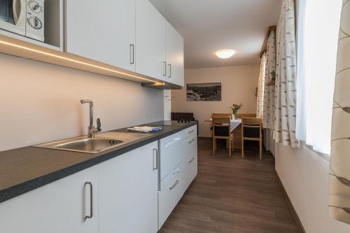 a kitchen with white cabinets and a sink and a table at Appartement Haus Zalim in Brand