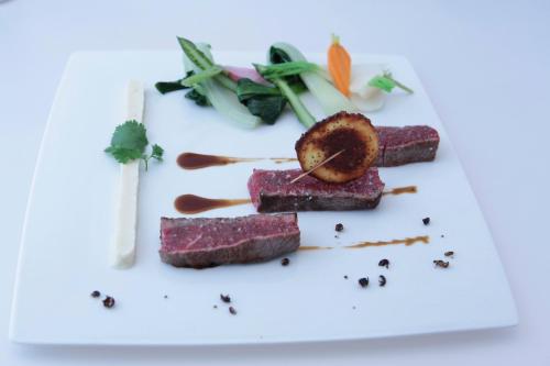 a plate of food with meat and vegetables on it at Logis Hôtel Restaurant Gilles Moreau Laguiole in Laguiole