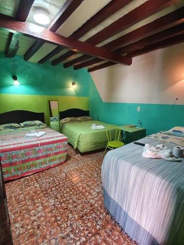 2 Betten in einem Zimmer mit grünen Wänden in der Unterkunft Hotel Kasa Kamelot Central in Quetzaltenango