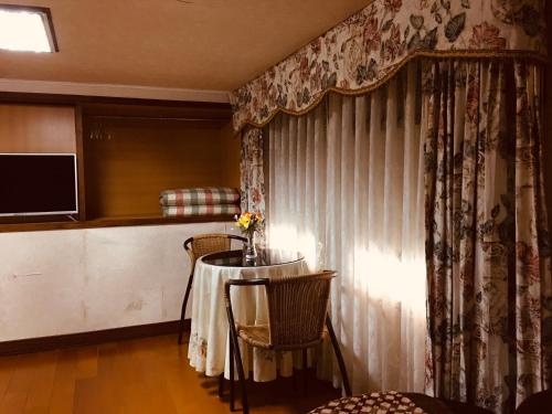 a room with a table and chairs and a television at Chulu Wenxin Xiao Zhan Homestay in Chulu