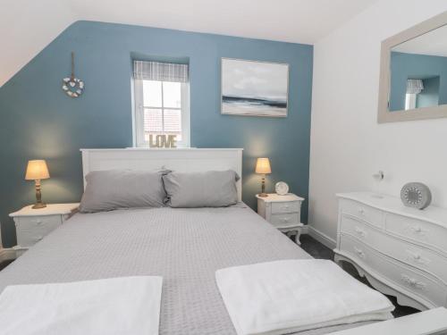 a bedroom with a bed and a blue wall at Causeway Cottage in Filey