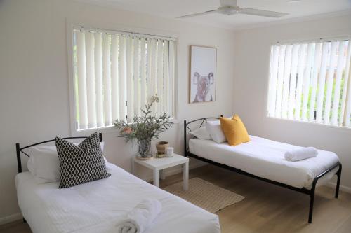 2 Betten in einem Zimmer mit weißen Wänden und Fenstern in der Unterkunft Beaches 1 -LJHooker yamba in Yamba