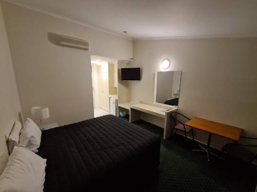 een hotelkamer met een bed en een bureau bij Cottonwood Motor Inn in Mildura