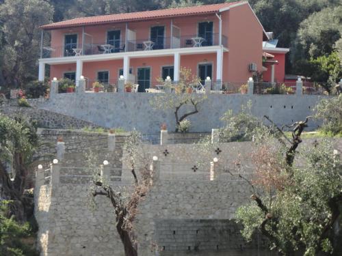 a pink house on top of a stone wall at Stamatela Studios in Paleokastritsa