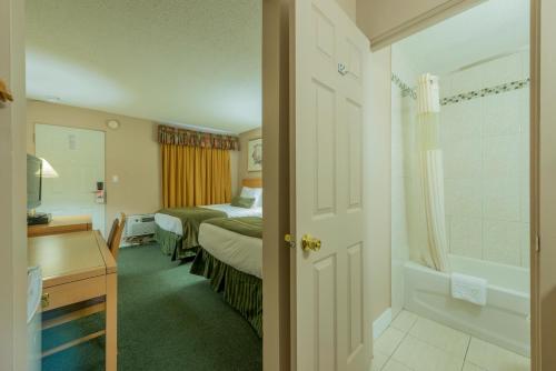 a hotel room with a bed and a bathroom at Howard Johnson by Wyndham Downtown Kamloops in Kamloops