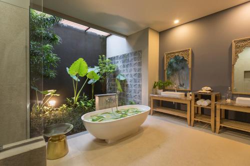 ein Badezimmer mit Badewanne und großem Spiegel in der Unterkunft Villa Daun Canggu by Premier Hospitality Asia in Canggu