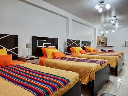 Cette chambre comprend 3 lits avec des oreillers colorés. dans l'établissement Cusco Magico 6 - Mini Departamento Santa Ursula, à Cusco