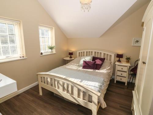 a bedroom with a white bed and two windows at Tan Bryn 2 in Aberdaron