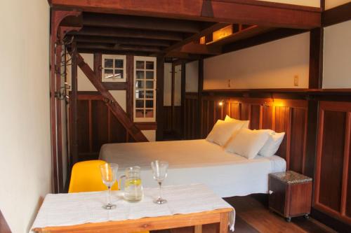 a bedroom with a bed and two tables with wine glasses at Casa de Hospedagem Paraty in Paraty