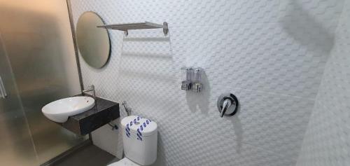 a white bathroom with a toilet and a sink at RedDoorz Plus near Siloam Hospital Balikpapan in Balikpapan