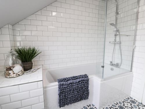 a white bathroom with a shower and a tub at The Fox's Den in Whitby