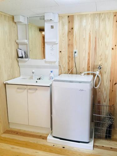 a bathroom with a sink and a washer and dryer at 古民家宿　寝つきいいキツネ in Shimanto