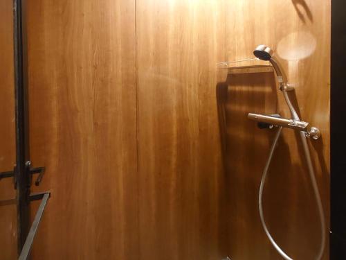 a shower in a bathroom with a wooden wall at Granbell hotel Tanuki, Sapporo in Sapporo