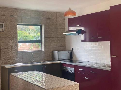 uma cozinha com armários roxos, um lavatório e uma janela em Elegant84 em Joanesburgo