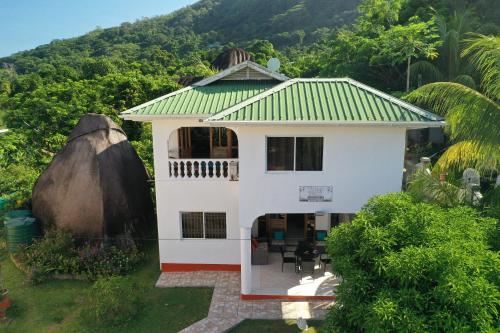 a white house with a green roof at Josies Cottage in Beau Vallon