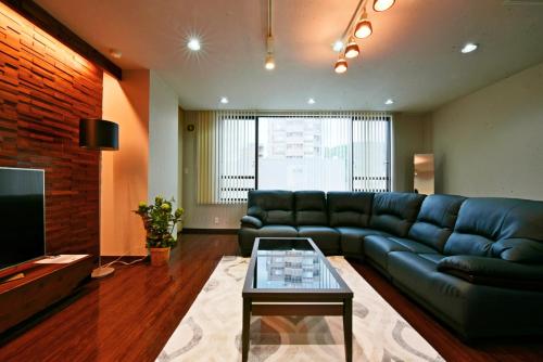 a living room with a couch and a tv at Hostel PLEASURE MARUYAMA in Sapporo