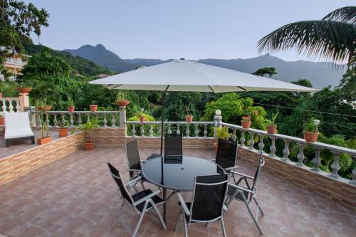 a table with chairs and an umbrella on a patio at Josies Cottage in Beau Vallon
